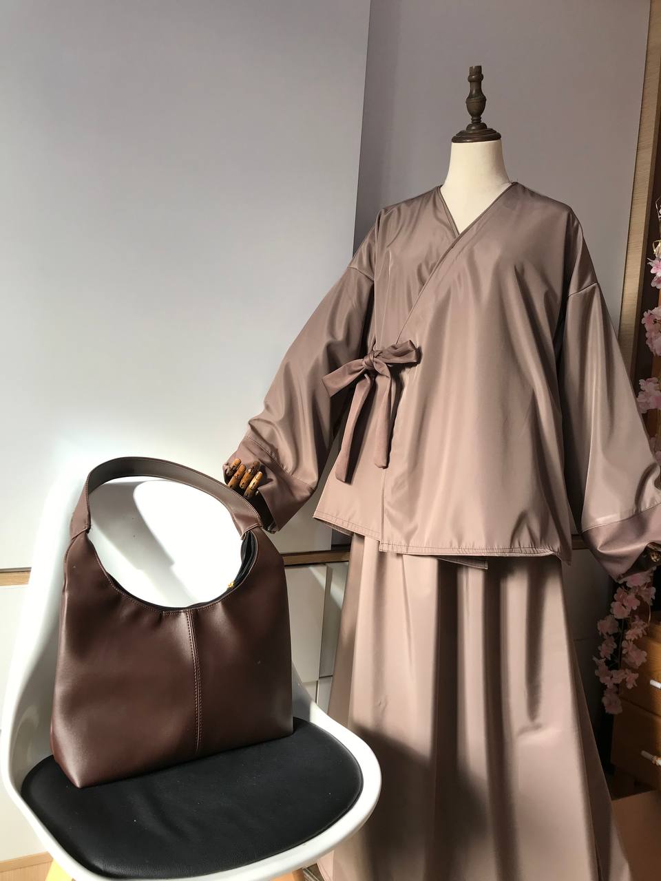 Brown traditional outfit on a mannequin with a matching bag on a chair.